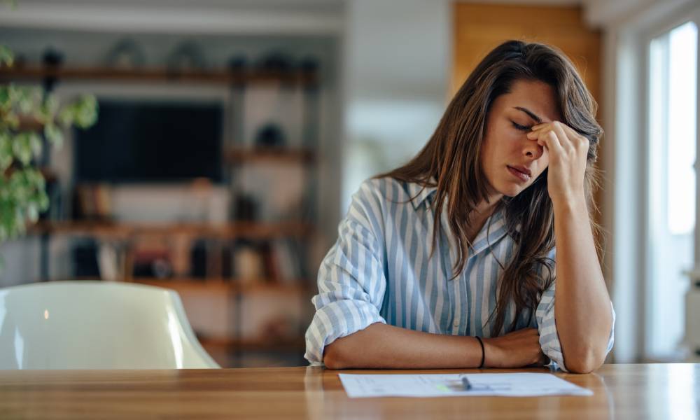 A mother sitting at a table with legal documents and feeling stressed about her upcoming child custody case.