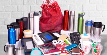 Assorted promotional products, including thermoses, mugs, gifts, sleep masks, power banks, pens in boxes, and notebooks.