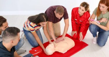 Two CPR instructors guiding a class of students through the steps of performing proper CPR techniques.