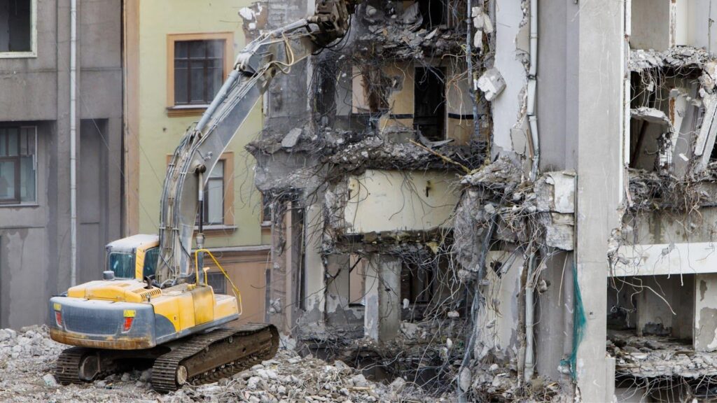 An excavator actively demolishing a historic building, highlighting the importance of careful and strategic dismantling to preserve architectural elements and minimise environmental impact, as part of responsible urban redevelopment.