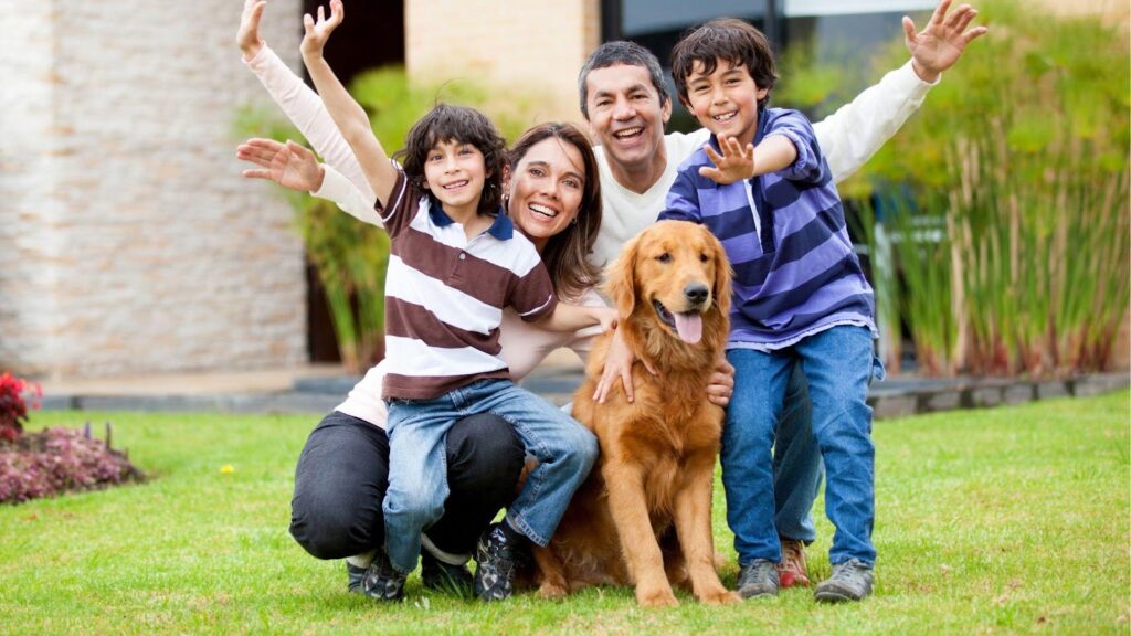 A happy family of four, including two children and their golden retriever, posing and smiling together on a grassy lawn, radiating joy and togetherness.