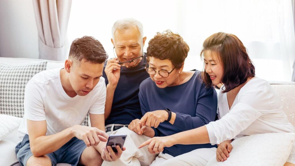 A multi-generational family engaging happily around a smartphone in a bright, modern living room, exemplifying a stylish and functional home adapted for life after raising children.