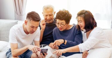 A multi-generational family engaging happily around a smartphone in a bright, modern living room, exemplifying a stylish and functional home adapted for life after raising children.