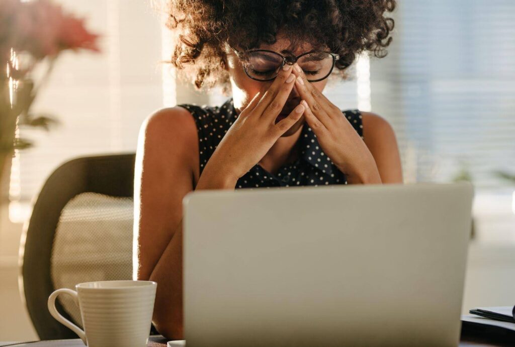 A woman feeling stressed while working on her laptop at home, symbolising the challenges of managing stress and turning it into a springboard for success. 