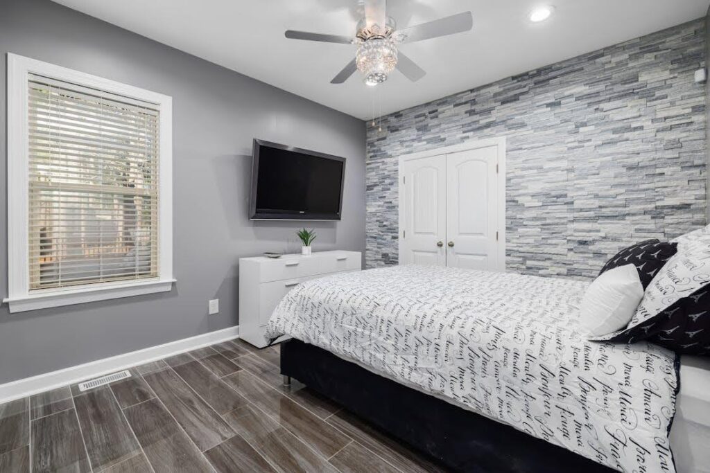 Modern teenager's bedroom featuring a stylish bed with patterned bedding, a stone accent wall, and a wooden floor, ideal for illustrating how aluminium shutters can transform a teen's personal space.