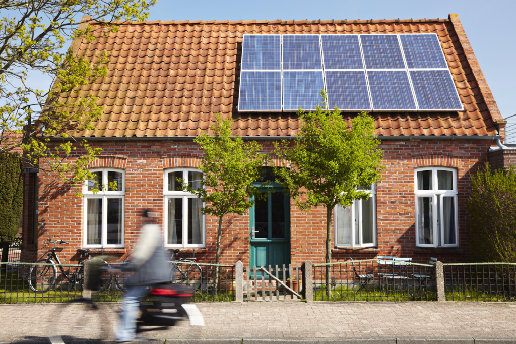 a regular single story residential home, with one half of the roof occupied with solar panels. 