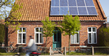 a regular single story residential home, with one half of the roof occupied with solar panels.