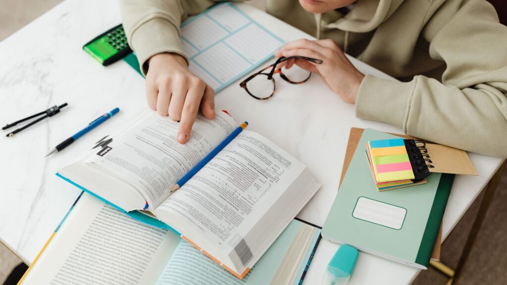 a student studying pointing his finger in the textbook