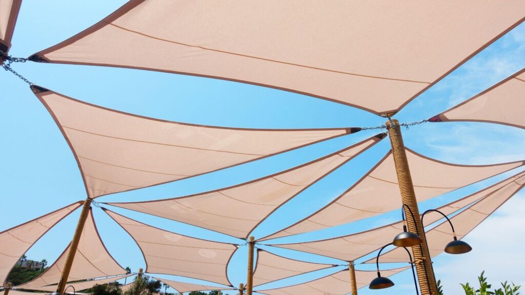 Multiple interconnected shade sails against a clear blue sky, providing cool shade and demonstrating stylish outdoor setup ideas for weekend DIY projects.