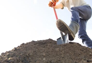 Person digging with a shovel in soil, emphasising safe digging practices for home gardeners.